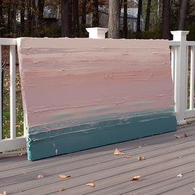 A peach, coral, pale pink and teal thick textured painting leaning outside on a deck in natural light by Teodora Guererra.