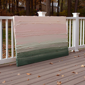 A light Coral, light pink, celadon and hunter green thickly textured abstract painting by Teodora Guererra leaning outside on a deck.