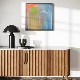 A blue, orange and green abstract print framed in a white oak floater frame by Teodora Guererra hanging on a white wall over a mid century modern console with a black lamp.