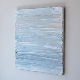 An abstract painting with thick impasto brushstrokes of blue and yellow paint is seen at an angle on a gallery wall.