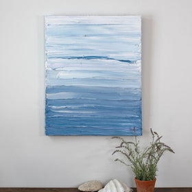 A painting is hung above a shelf. It is decorated in blue and white paint applied in thick impasto streaks to its canvas surface. Wired and ready to hang.