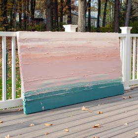 A peach, coral, pale pink and teal thick textured painting leaning outside on a deck in natural light by Teodora Guererra.