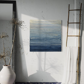 A blue, beige, lavender and light yellow textured abstract painting by Teodora Guererra hangs on a wall over a blue ceramic floor. To the right is a decorative ladder with a white silky fabric hanging and to the left a ceramic pot with some decorative branches in front of a wall mirror.