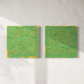 Two square abstract text based paintings with thick green paint and tangerine gestural lines, displayed side by side on a light textured wall.