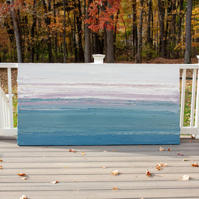 A white, lavender, teal and blue abstract heavily textured painting like sculpture by Teodora Guererra leaning outside in natural light on a deck.