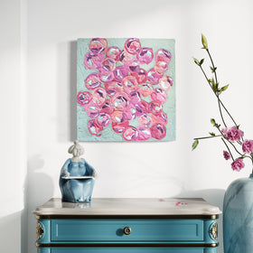 A very textured abstract painting with celadon background and circle type abstract flowers in pink, peach, plum and white hangs on a white wall above a teal end table with a white marble top.