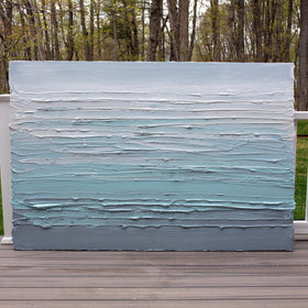 An abstract painting with turquoise impasto brushstrokes in a color gradient is sitting on the artists deck outside.