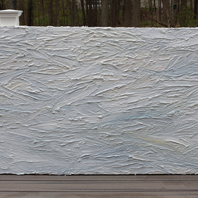 A white and light blue abstract painting with thick, impasto brushstrokes sits on a deck at the artists studio.