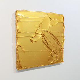 A golden textured painting by Teodora Guererra is seen at an angle on a gallery wall.