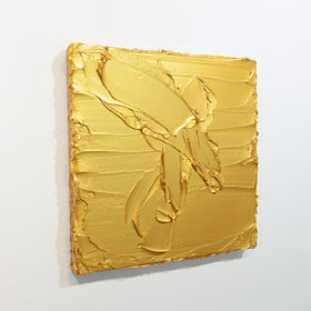 A golden textured painting by Teodora Guererra is seen at an angle on a gallery wall.