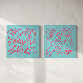 Two square abstract text based paintings hanging side by side on a textured off-white wall. The canvases are light teal blue with thick, raised pink scribbled lines across them.