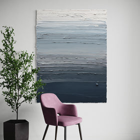 A dark grey blue, light blue, blue green, and white thickly textured abstract painting hangs on a white wall by Teodora Guererra. In front of the painting is a chair with dark metal legs covered in a pink/lavender colored fabric. To the left of the chair is a potted fica tree.
