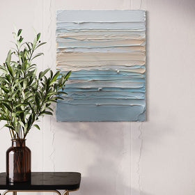 A thickly painted painting in white, orange sherbet and teal blue by Teodora Guererra hangs on a white stucco wall over and to the left of a dark marble end table with brass legs. On the table is an amber glass vase with eucalyptus branches.