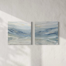 A pair of coastal paintings with blue, grey, white, cream, stone, teal, and yellow ochre paint hanging on a white wall by Teodora Guererra.