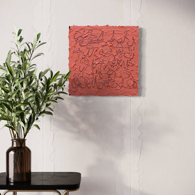 A abstract painting with navy text based line drawings on a muted coral-red background, displayed on a white wall above a black side table with a green plant in a dark amber vase.