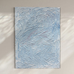 A blue and white textured painting hangs on a white wall.