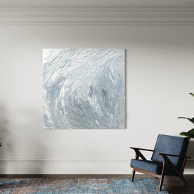 A Grey blue, light blue, lavender, celadon and white thickly textured abstract painting hanging on a white wall in natural light in a room with a blue chair by Teodora Guererra.