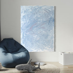 A blue and white textured painting hangs on a white wall above a Childs blue bean bag chair. A shark stuffed animal sits on the floor.