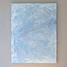 A blue and white textured painting hangs on a grey wall in the artists studio.