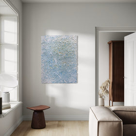 Modern living room with an original abstract textured painting by Teodora Guererra on the wall, brown stool, and beige sofa.