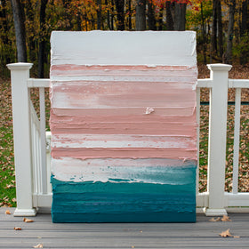 A peach, coral, white and teal with lavender thick textured painting leaning outside on a deck in natural light by Teodora Guererra.