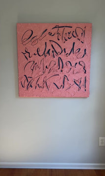 A video of a coral/pink text based painting featuring navy abstract calligraphic lettering, displayed against a neutral light gray wall.