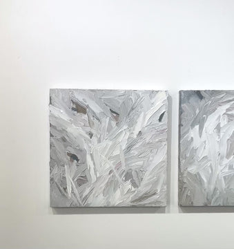 A video of a pair of thickly textured paintings in grey, white, blue grey and plum grey by Teodora Guererra hanging on a white wall.