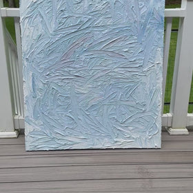 A video of a blue and white textured painting leaning on a deck in the artists studio.