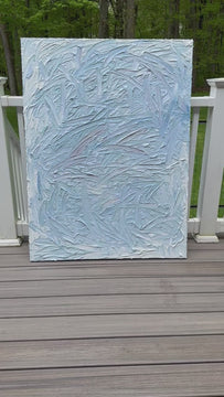 A video of a blue and white textured painting leaning on a deck in the artists studio.