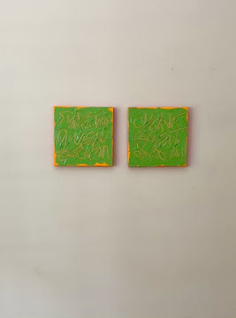 a video of two square abstract text based paintings with thick green paint and tangerine gestural lines, hanging on a white wall.