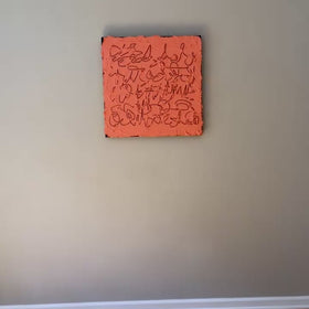 A video of a square abstract painting with a textured coral-pink surface and dark calligraphic line work, mounted against a light gray wall.