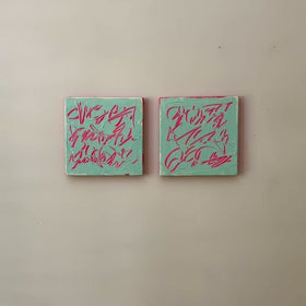 A video of two square abstract text based paintings hanging side by side on a textured off-white wall. 