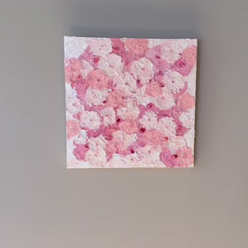 A video of a very textured abstract painting with white background and circle type abstract flowers in pink and white hanging on a grey wall.