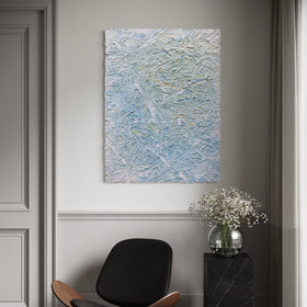 Textured original abstract painting by Teo Guererra on a wall above a modern chair and side table with flowers.