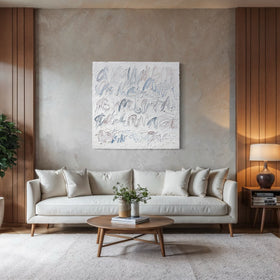 A modern living room featuring a light beige sofa with white pillows, a round wooden coffee table, a large potted green plant, and a textured abstract canvas painting on the wall above the sofa.