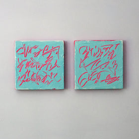 Two square abstract text based paintings with turquoise backgrounds and pink scribbled lines, displayed side by side on a light gray wall.