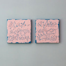 Two square abstract texted based paintings with textured pink surfaces and teal outlines, mounted side by side on a light gray wall.
