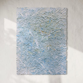 Original abstract textured painting by Teodora Guererra with blue and white tones hanging on a white wall with sunlight cascading over.