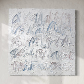 An abstract text based painting featuring textured, impasto brushstrokes in shades of light blue, gray, and off-white, mounted on a neutral beige wall.