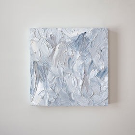 A painting is hanging on a wall. Its surface is decorated with white, blue and grey paint in a thick impasto. Wired and ready to hang