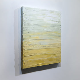 A Yellow, seafoam green and white textured painting by Teo Guererra hangs on a wall, side view.